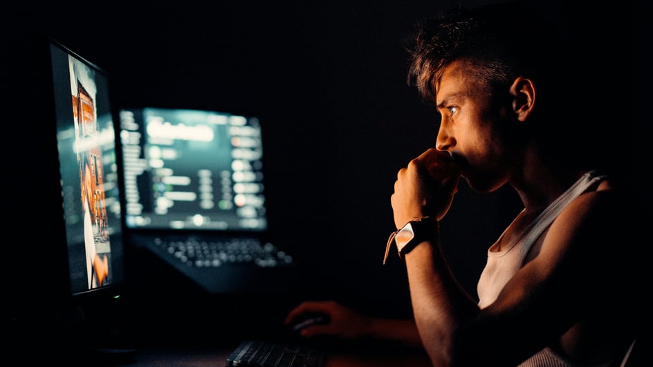  Person sitting at a computer, using AI video editing apps