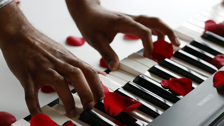  A pair of hands play royalty free Valentine’s music on a piano covered in rose petals.