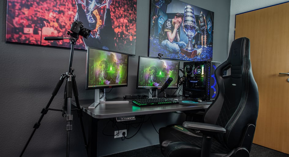  A video streaming setup with a gaming chair, a camera, 2 monitors, and colourful wall art is ready for live streaming using copyright free music for streaming.