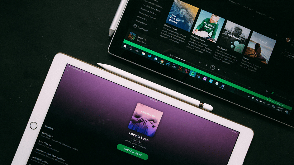  Two tablets sit side by side with the Spotify app open, as the users wonder, “How much does Spotify pay?”