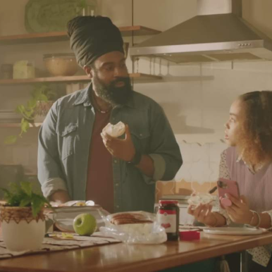 Man and woman in kitchen discussing music licensing companies and music sync rights over breakfast preparation.