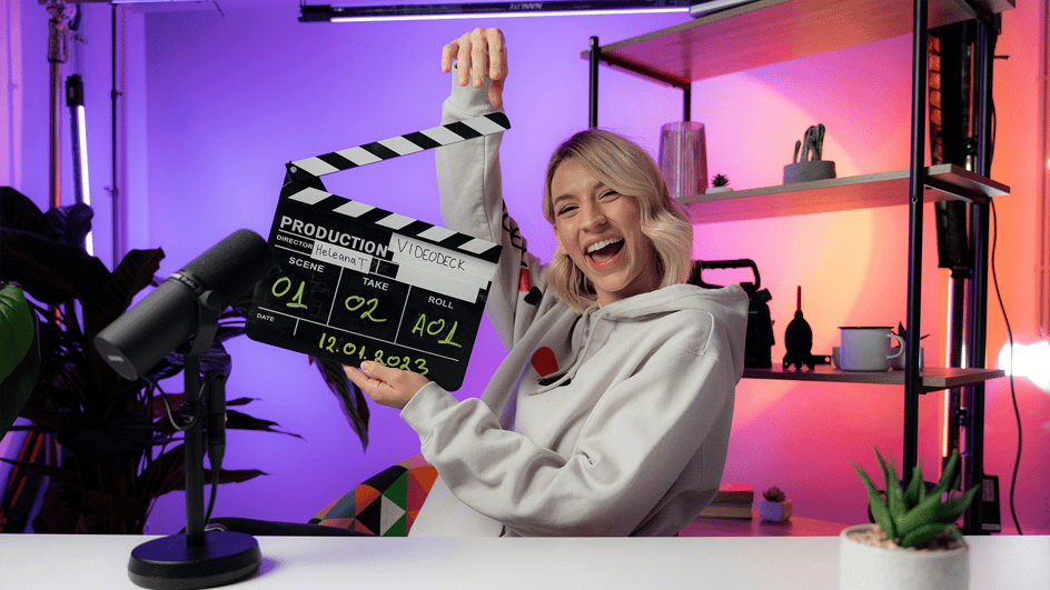 A woman holds up a film slate, ready to record a video, using royalty free comedy music.