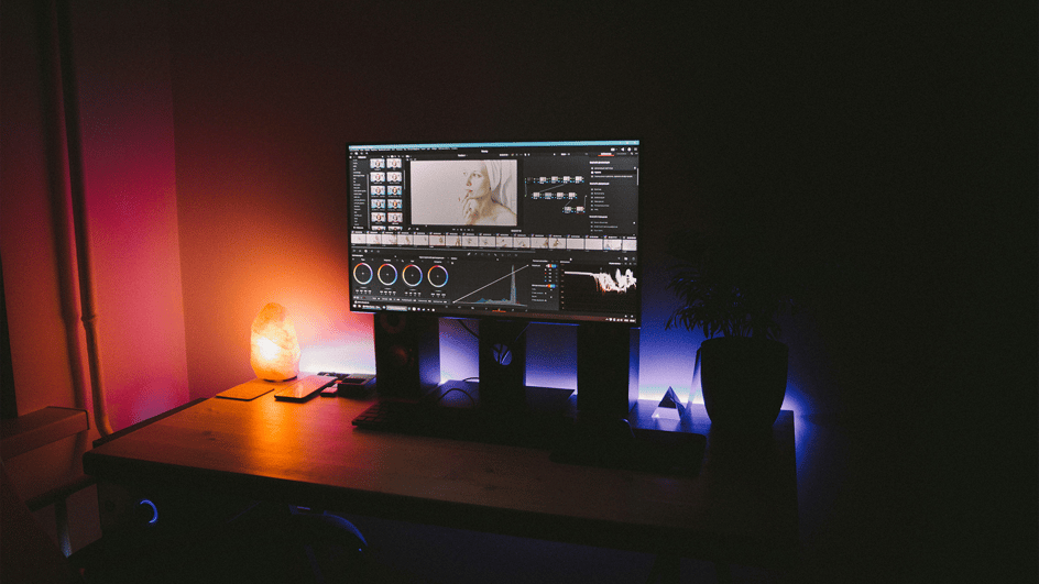  A computer monitor sits atop three speakers in a dark room, displaying the DaVinci Resolve AI editing software.