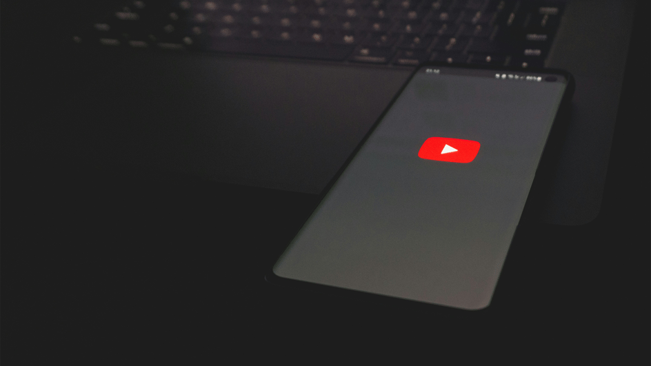  Cell phone sitting on laptop, loading a video about how to avoid demonetization on YouTube