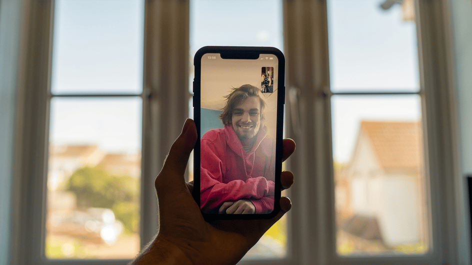  A man on a smartphone, video chatting with his friend about the new maximum length of YouTube Shorts, 3 minutes long.